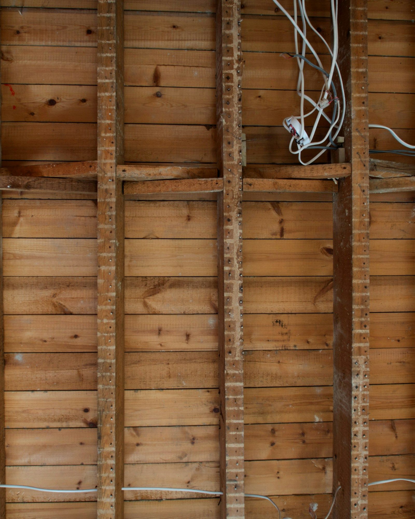 Exposed timber stud wall with electrical cabling threaded through before boarding