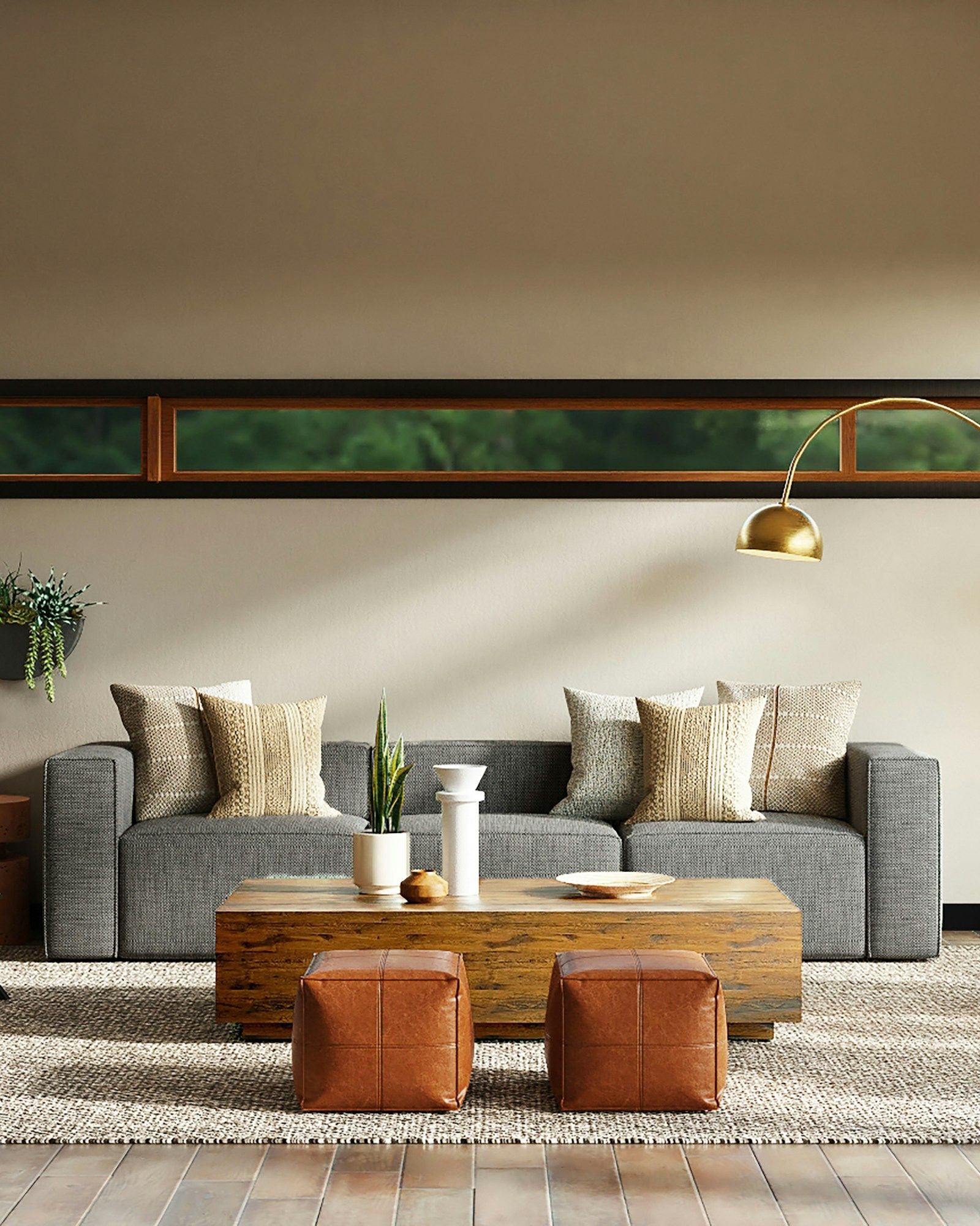 Sitting area with a charcoal sofa, woven cushions and leather ottomans beneath a brass arc lamp